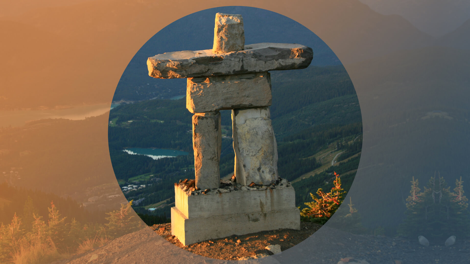 An inukshuk in Whistler, BC, with lake and mountains in the background