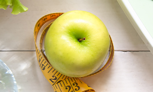 Green apple , scale, water bottle, lettuce and measuring tape on a white background.